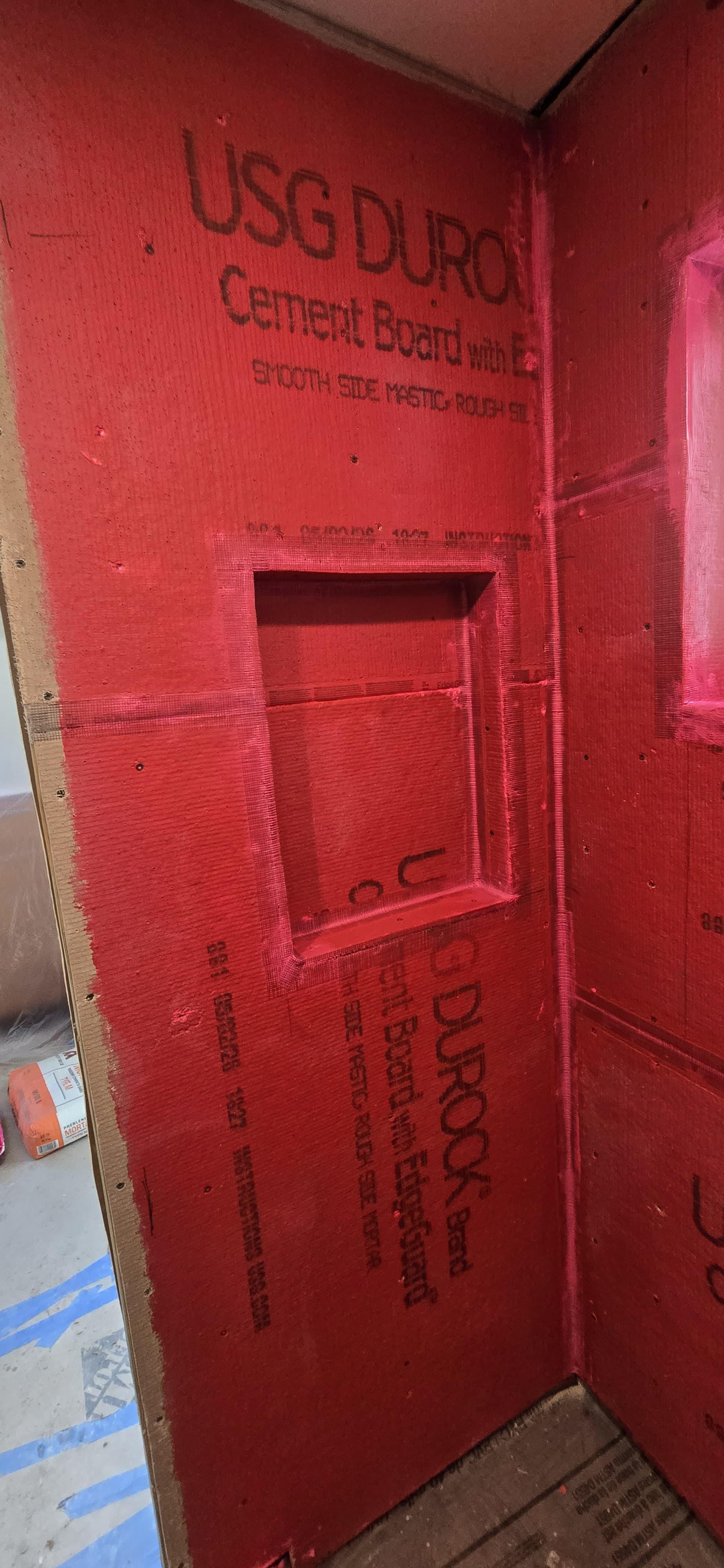 Pared de ducha con impermeabilizante rojo y nicho empotrado